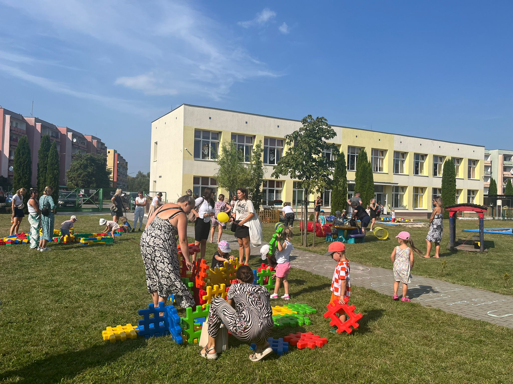 biały budynej przed którym bawią się dzieci