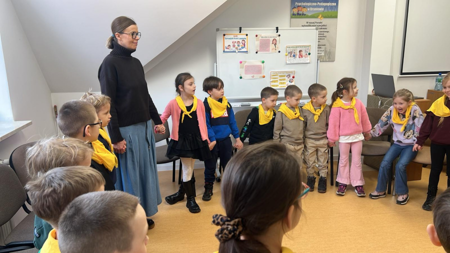 Dzieci z żółtymi chustami stoją w kręgu podczas wspólnych warsztatów